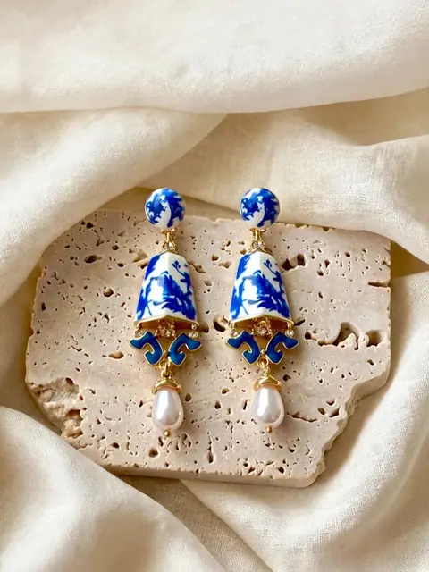 Aretes colgantes azules y blancos con perla, sobre una piedra