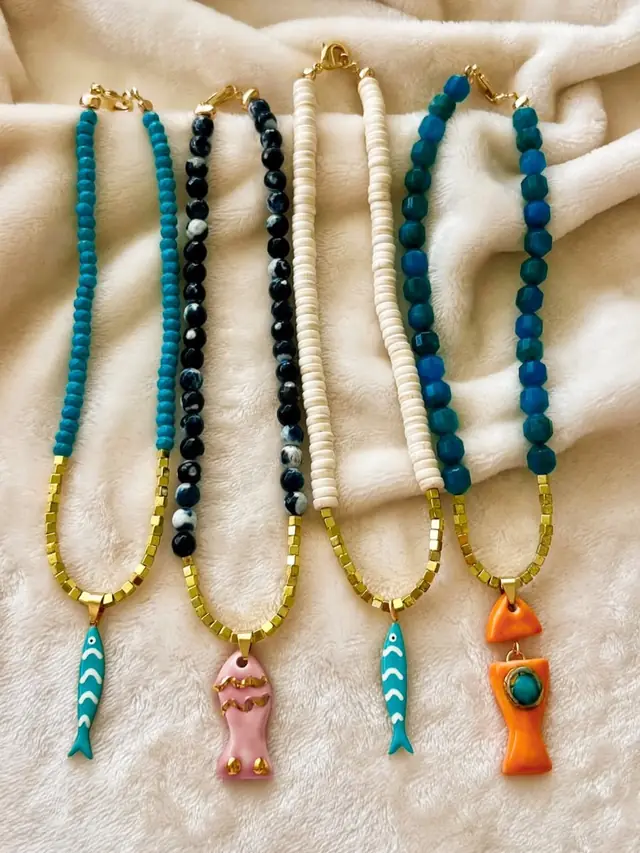 Cinco collares de cuentas con peces de cerámica turquesa, rosa y naranja