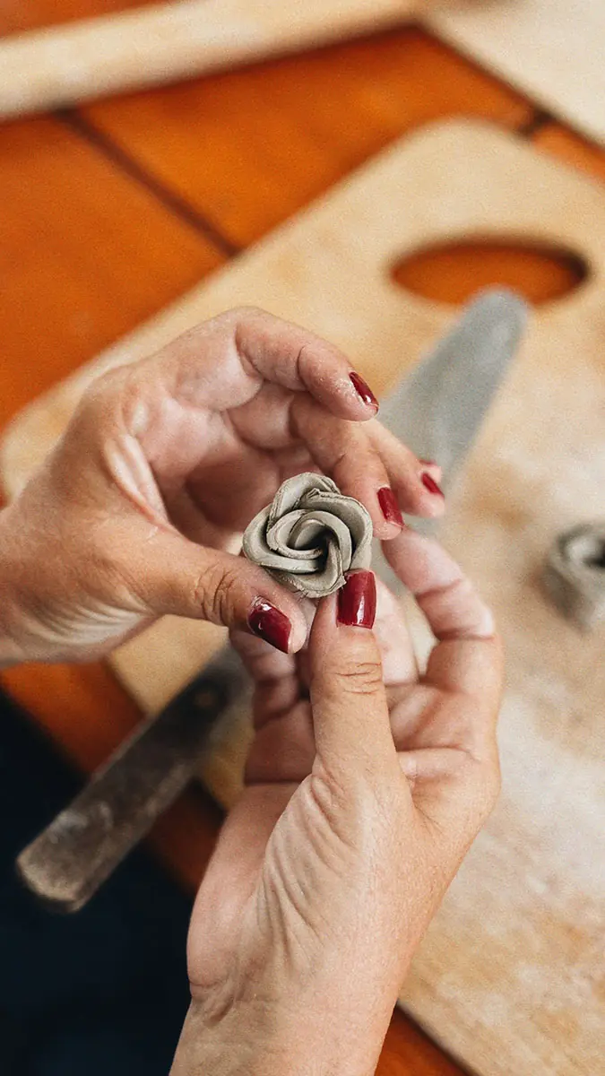 Manos dando forma a una pieza de arcilla sobre una tabla de madera
